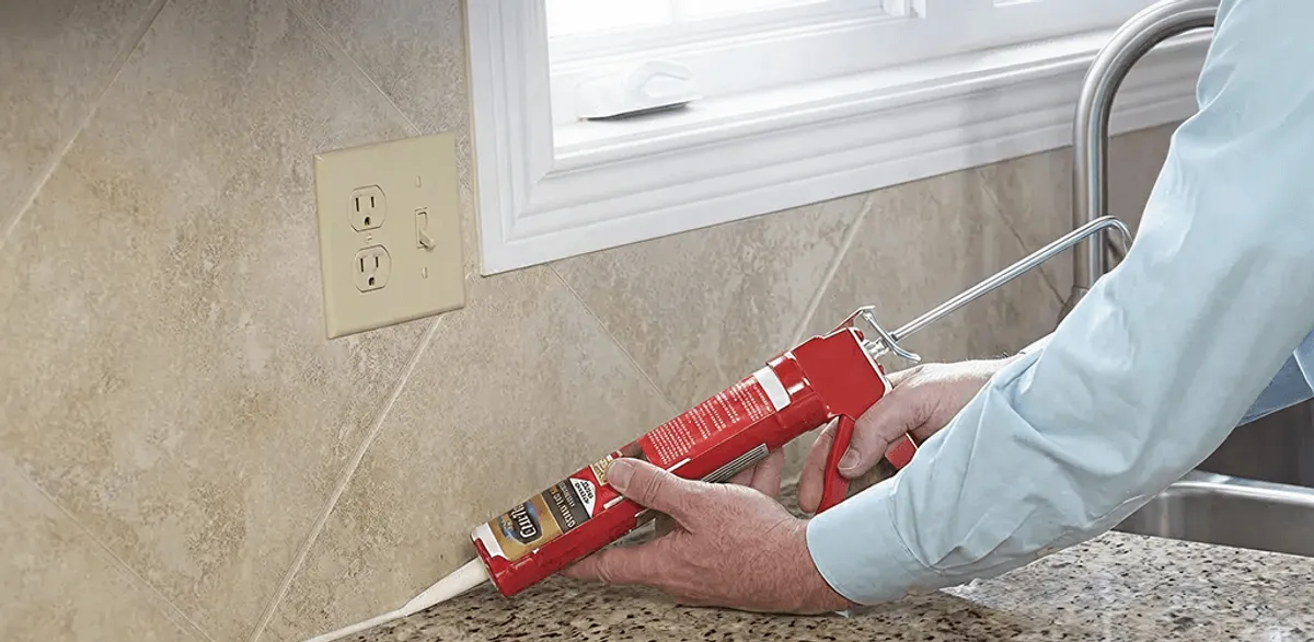 Handyman applying caulk along a kitchen backsplash and countertop seam in Anaheim, CA